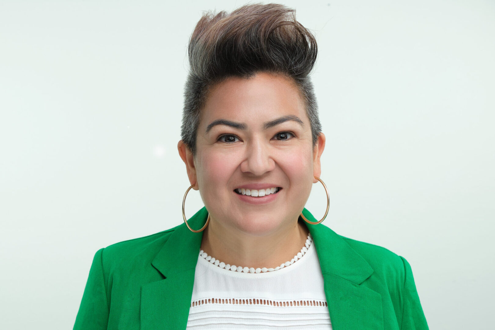 A woman in green jacket and white shirt smiling.