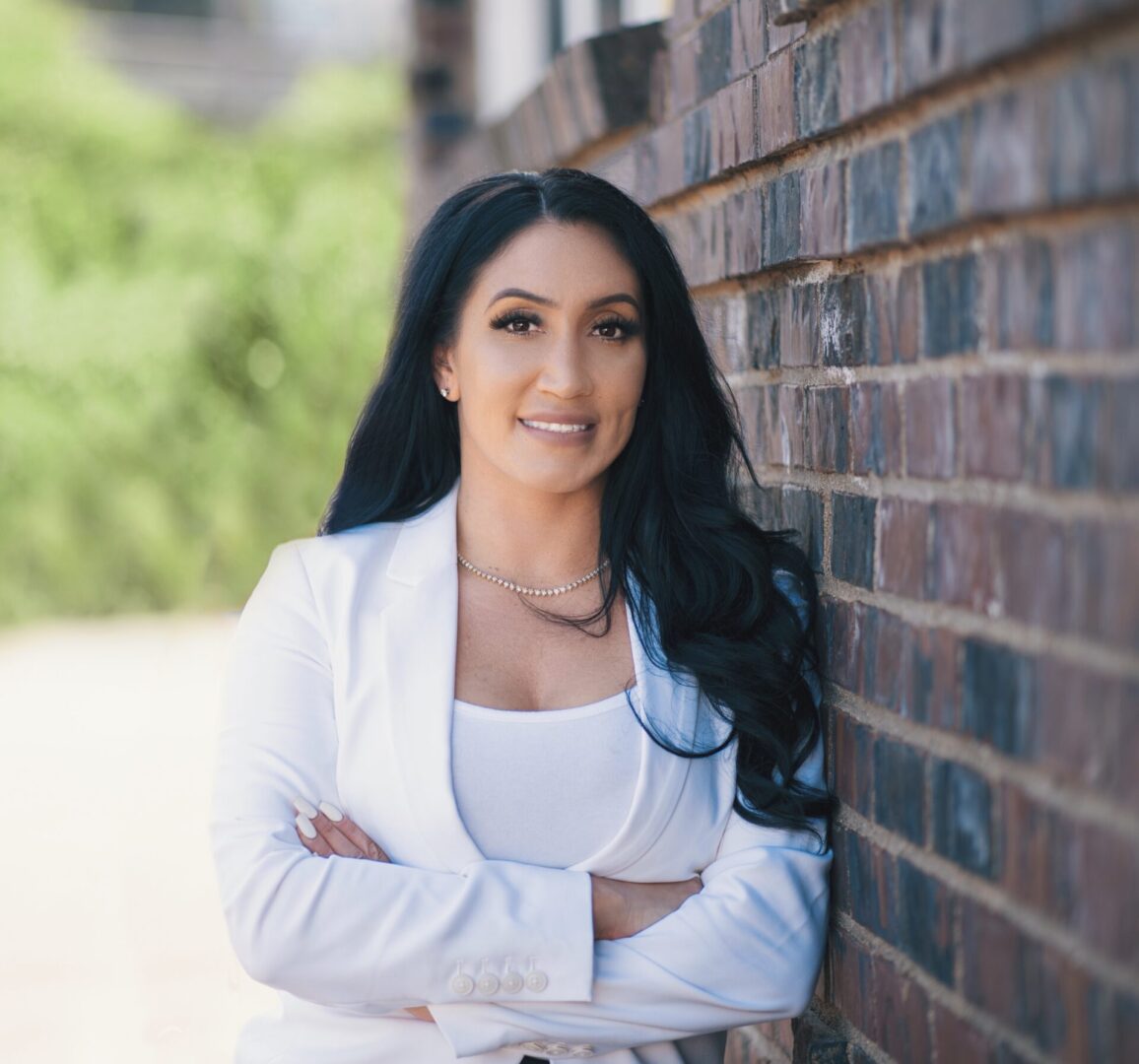 A woman standing in front of a brick wall.