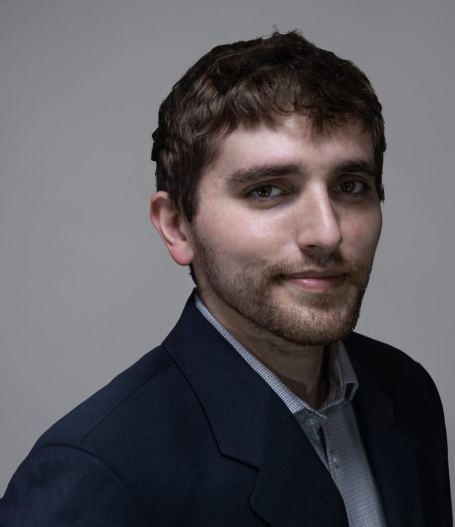 A man in a suit and tie smiling for the camera.