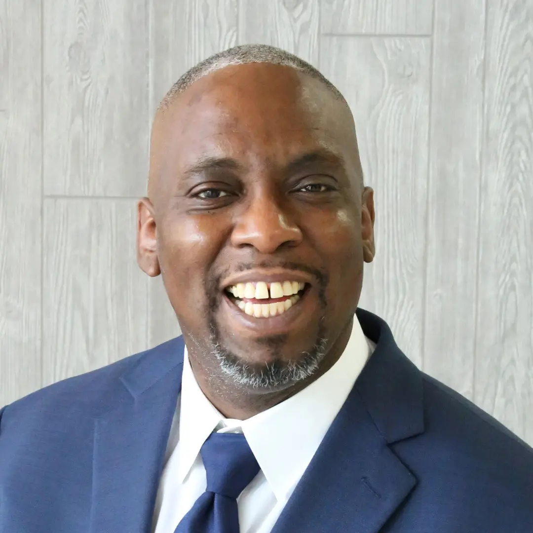 A man in a suit and tie smiling for the camera.