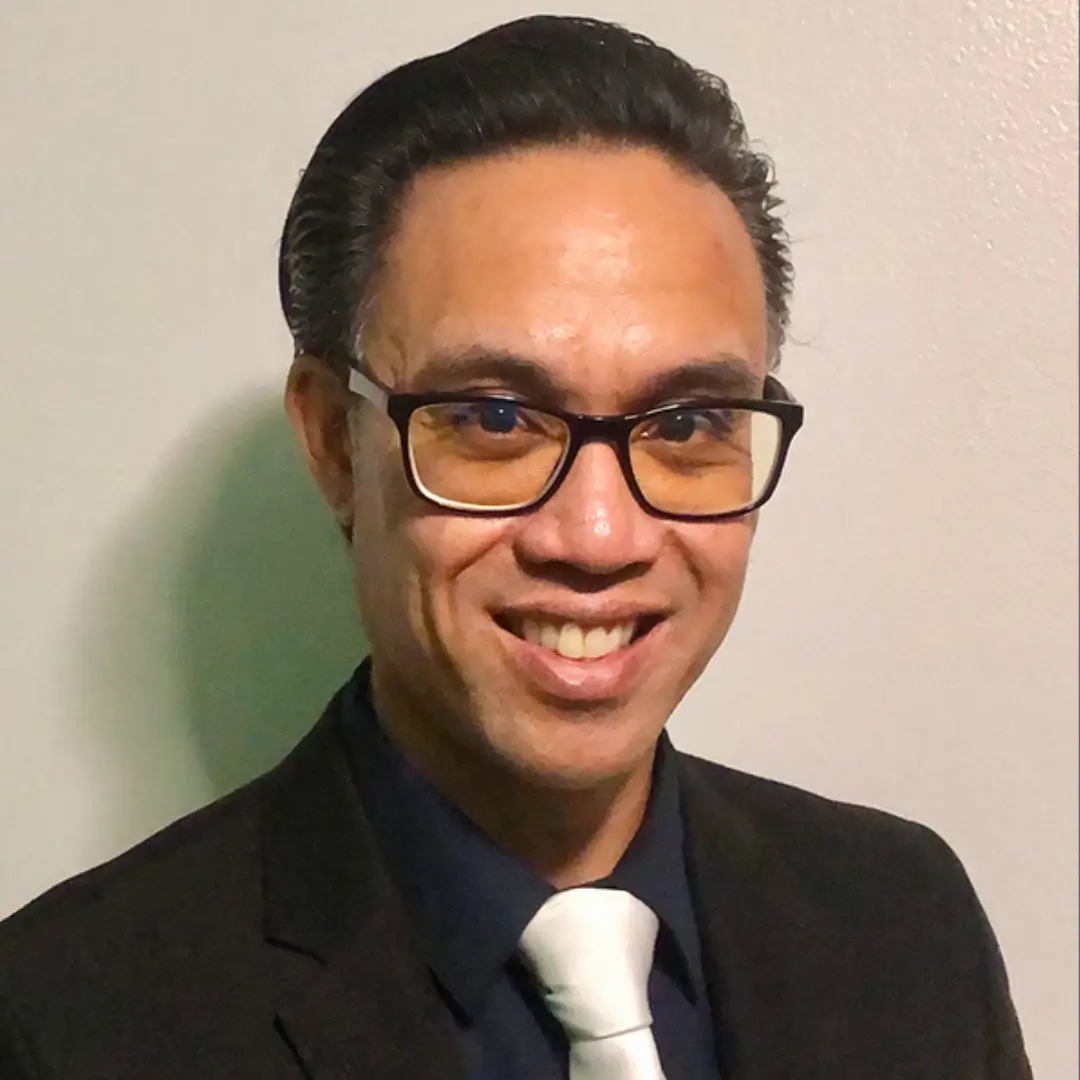 A man in a suit and tie smiling for the camera.