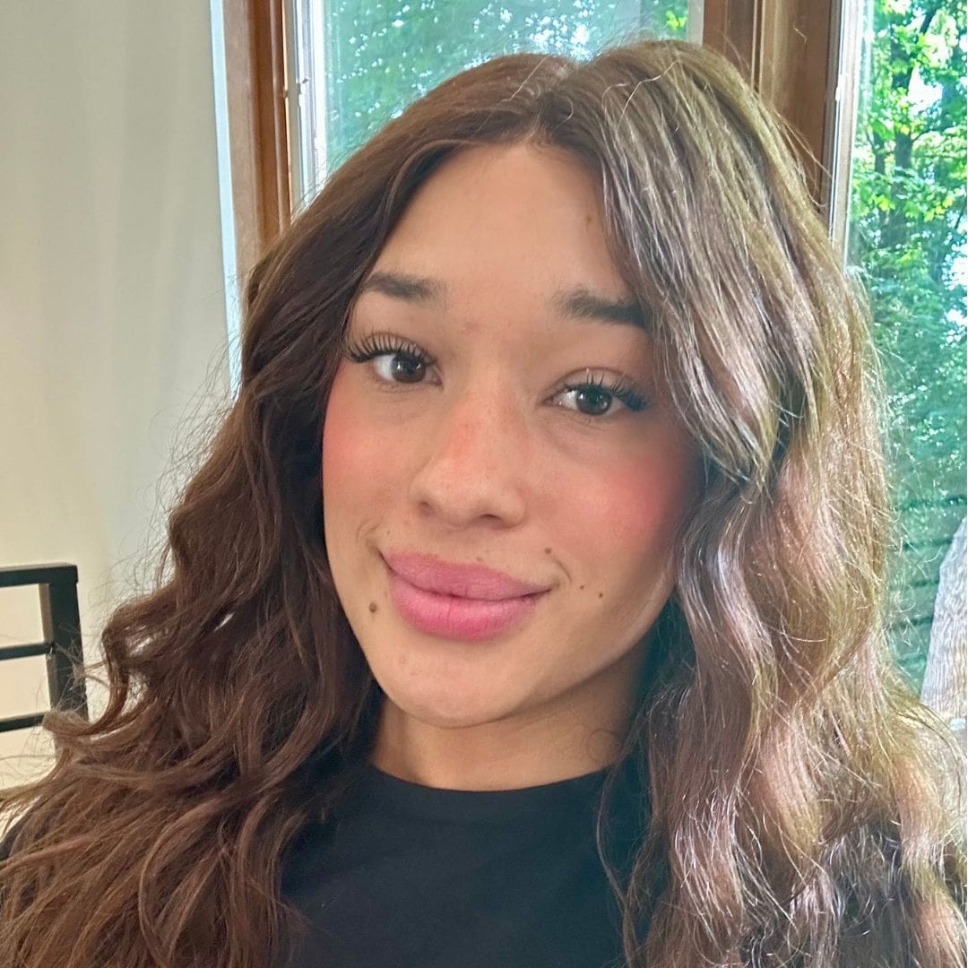 Smiling person with long hair indoors.