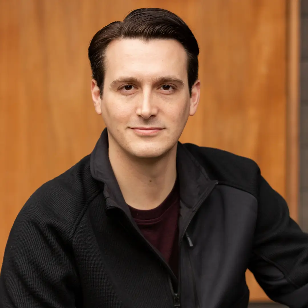 Man in black jacket, wooden background.