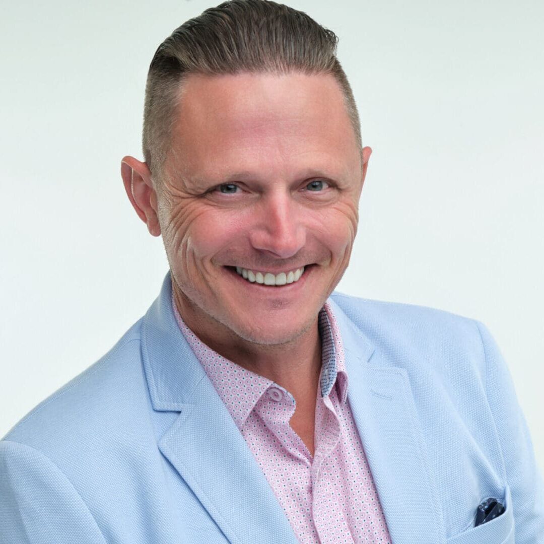 A man in a blue suit and pink shirt.