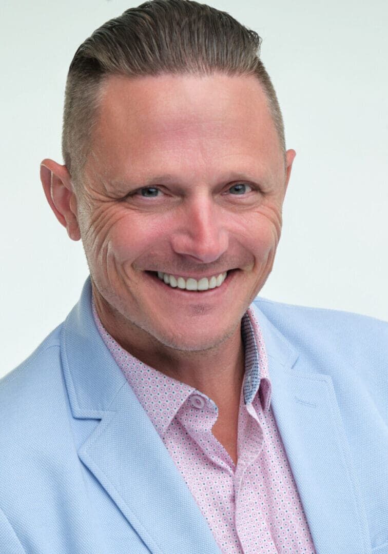 A man in a blue suit and pink shirt.